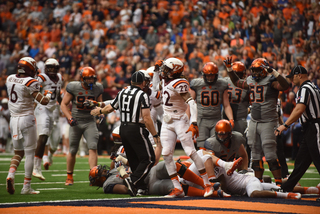 Syracuse offensive lineman Aaron Roberts signals for a touchdown as players get up at the end of a play. 