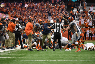 Several players lie on the ground as Syracuse defensive line coach Vinson Reynolds talks to a referee. SU defensive lineman Chris Slayton raises his hand while running toward the sideline. 